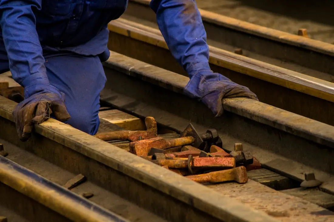 Mains gantées d'un ouvrier ferroviaire au travail sur des rails, formation pratique SECUFER Bordeaux